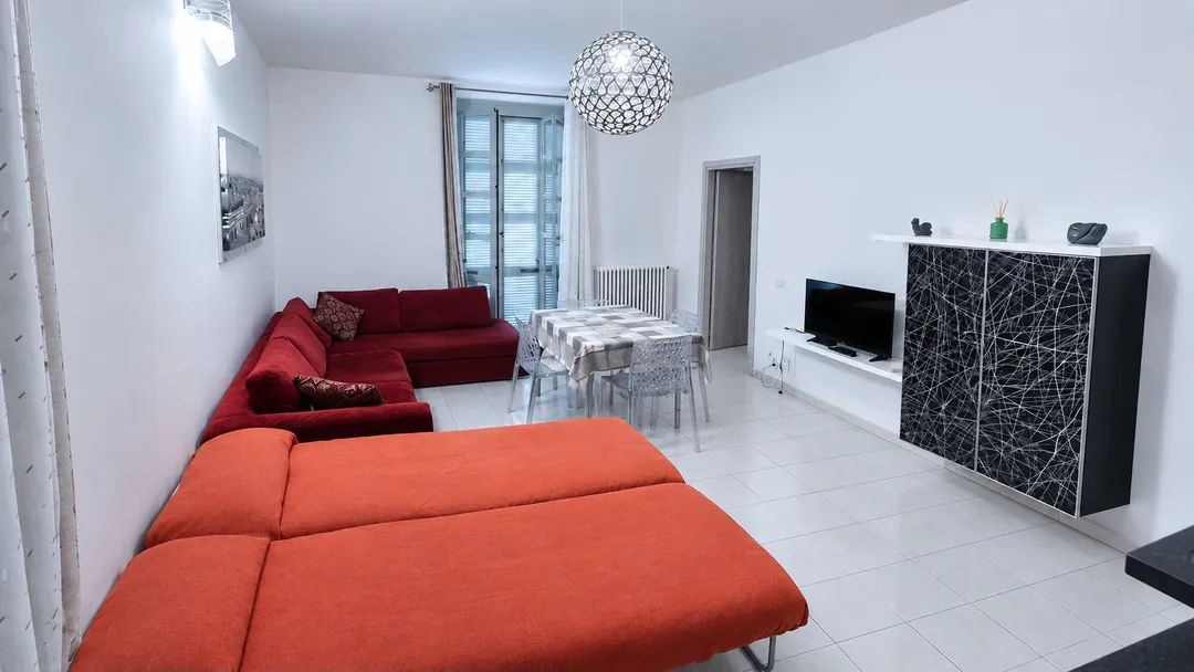 Living room with two open puff beds, red sofa, dining table and TV